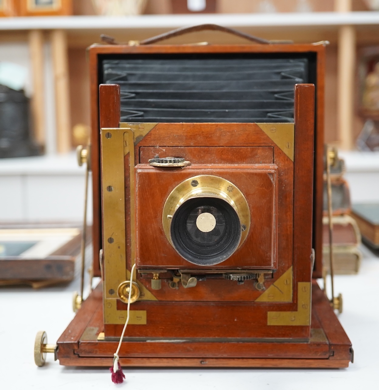 A late 19th/early 20th century brass and mahogany half plate bellows camera with a lens and a shutter action by Thornton Pickard. Condition - glass missing